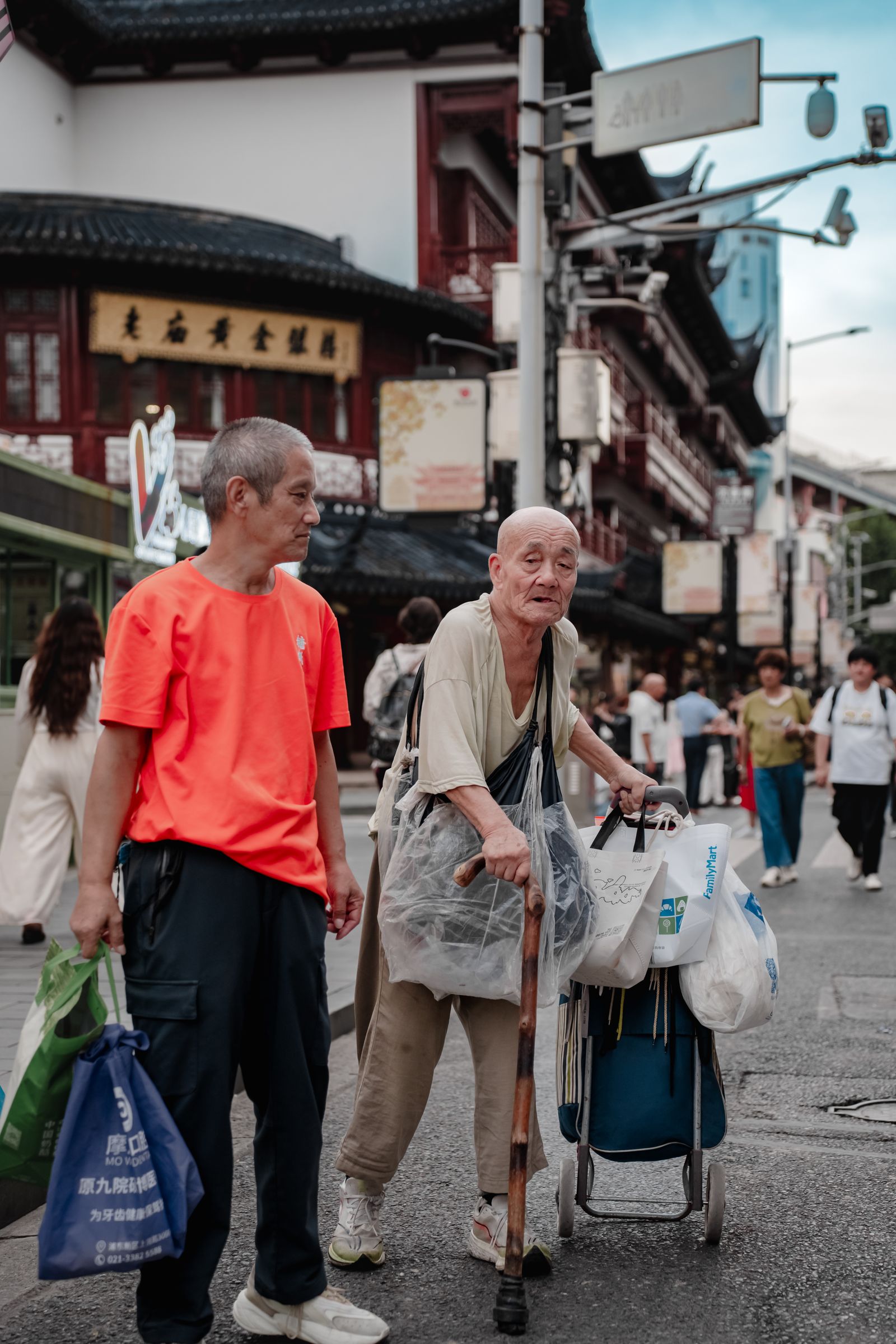 亚洲城市街道中家人辅助老人步行，象征家庭介护支持